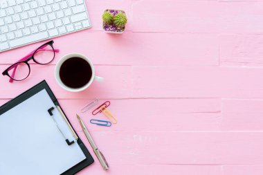 Üstten görünüm Ofis masaları dahil olmak üzere klavye, Gözlük, klipler, çiçek, kalem, Not defteri, belge ve kahve pembe ahşap arka plan üzerinde kırpma çalışma alanı ve ofis aksesuarları ile.