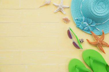 Plaj aksesuarları dahil olmak üzere güneş gözlüğü, deniz yıldızı, şapka plaj, renkli flip flop ve deniz kabuğu parlak pastel ahşap arka plan için mavi yaz tatil ve tatil kavramı üzerinde.
