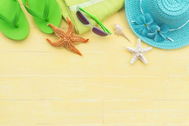Plaj aksesuarları, güneş gözlüğü, deniz yıldızı, şapka plaj da dahil olmak üzere retro kamera, sarı havlu, renkli flip flop ve deniz kabuğu parlak pastel ahşap arka plan için mavi yaz tatil ve tatil kavramı üzerinde.