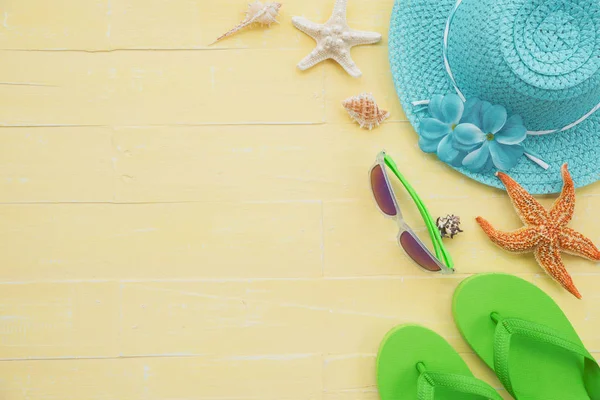 Plaj aksesuarları dahil olmak üzere güneş gözlüğü, deniz yıldızı, şapka plaj, renkli flip flop ve deniz kabuğu parlak pastel ahşap arka plan için mavi yaz tatil ve tatil kavramı üzerinde.