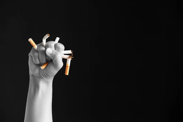 World No Tobacco Day, May 31. STOP Smoking. Close up Man hand crushing and destroying cigarettes on black background.