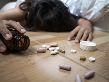 Kadın evde hapları aşırı doz sonra yerde yatıyor. Aşırı doz ve intihar kavramı.