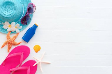 Plaj aksesuarları, güneş gözlüğü, deniz yıldızı, şapka plaj da dahil olmak üzere güneş kremi, renkli flip flop ve kabuk üzerinde parlak pastel ahşap arka plan için mavi yaz tatil ve tatil kavramı.