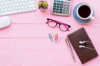 Üstten görünüm ofis masası çalışma alanı ve ofis aksesuarları dahil olmak üzere hesap makinesi, klavye, Gözlük, klipler, çiçek, kalem, Not defteri, kulaklık ve kahve pembe ahşap arka plan ile.