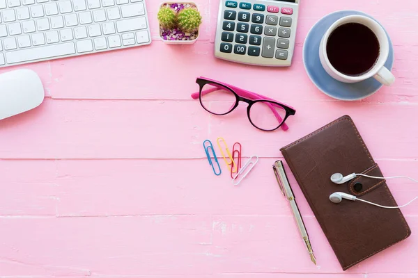 Üstten görünüm ofis masası çalışma alanı ve ofis aksesuarları dahil olmak üzere hesap makinesi, klavye, Gözlük, klipler, çiçek, kalem, Not defteri, kulaklık ve kahve pembe ahşap arka plan ile.