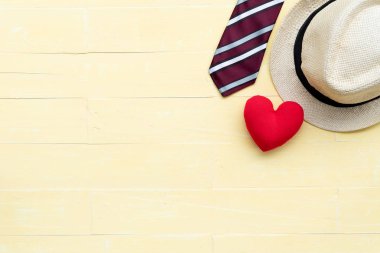 Mutlu babalar günü kavramı. Üstten görünüm kırmızı kravat, el yapımı kırmızı kalp ve şapka parlak sarı pastel ahşap masa arka plan üzerinde.