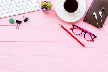 Üstten görünüm ofis masası çalışma alanı ve ofis aksesuarları dahil olmak üzere klavye, Gözlük, klipler, çiçek, kalem, Not defteri, kulaklık ve kahve pembe ahşap arka plan ile.