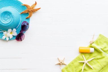 Beyaz plaj aksesuarları, güneş gözlüğü, deniz yıldızı, şapka plaj da dahil olmak üzere güneş kremi, yeşil havlu ve güneş kremi parlak pastel ahşap arka plan yaz tatil ve tatil konsepti için.