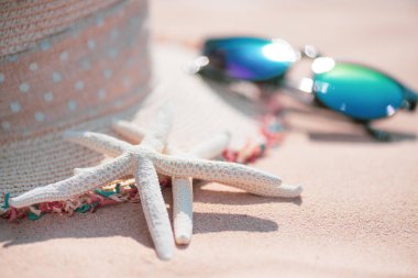 Deniz yıldızı yumuşak odak. Plaj aksesuarları dahil olmak üzere güneş gözlüğü, deniz yıldızı, kumlu plaj arka plan arka plan yaz tatil ve tatil kavramı için çiçek ve şapka kumsalda.