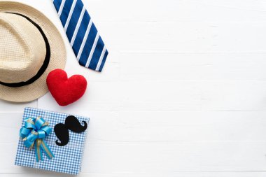 Mutlu babalar günü kavramı. Parlak beyaz pastel ahşap masa arka plan üzerinde kırmızı kravat, el yapımı kırmızı kalp, şapka ve güzel hediye kutusu bıyıklı üstten görünüm.