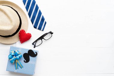 Mutlu babalar günü kavramı. Parlak beyaz pastel ahşap masa arka plan üzerinde kırmızı kravat, el yapımı kırmızı kalp, şapka ve güzel hediye kutusu bıyıklı üstten görünüm.