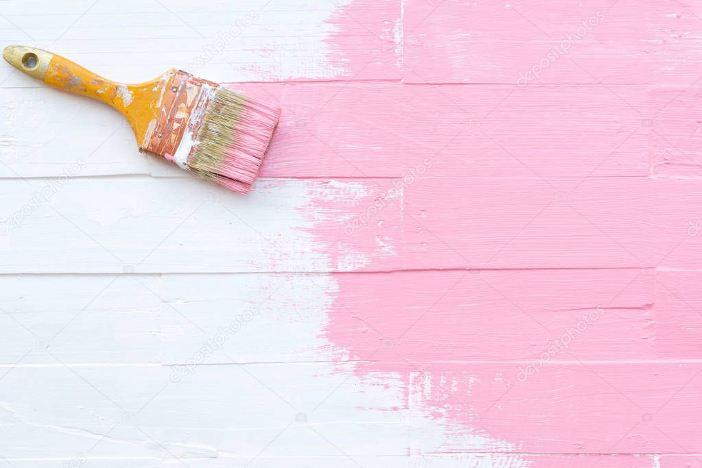 Close up paintbrush painting pink color on a white wooden table