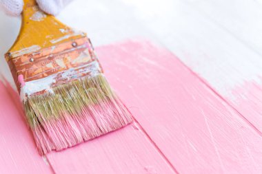Kadın el fırça boya pembe rengi beyaz ahşap bir masa üzerinde tutarak yukarı kapatın