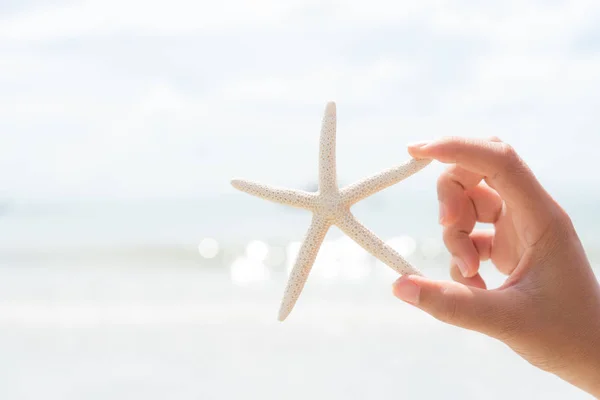妇女手举行海星在海和沙滩在背景下为暑假和假日概念 — 图库照片