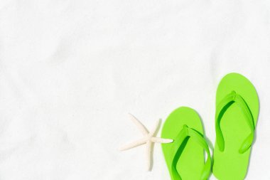 Yeşil flip flop koymak veya denizyıldızı yaz tatil ve tatil kavramı için beyaz kumlu plaj zemin üzerine adım.