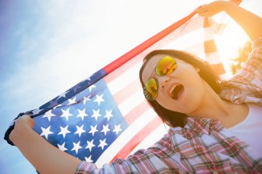 Amerika Birleşik Devletleri bayrağı tutarak ve kumsalda kollarını açarak kaygısız çalışan mutlu kadın kapatın. ABD Bağımsızlık günü kavramı.