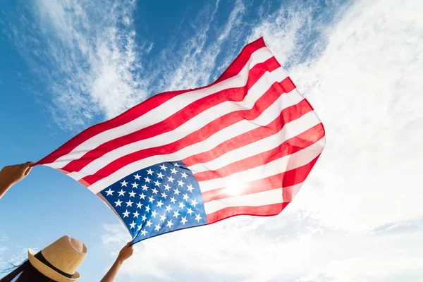 Amerika Birleşik Devletleri bayrağı tutarak ve koşma, mavi gökyüzü ile kollarını açarak kaygısız atlama genç mutlu kadın kapatın. ABD Bağımsızlık günü, 4 Temmuz.