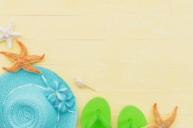 Güneş gözlüğü, deniz yıldızı, şapka plaj ve deniz kabuğu parlak sarı pastel ahşap arka plan üzerinde yaz tatil ve tatil kavramı için de dahil olmak üzere plaj aksesuarları.