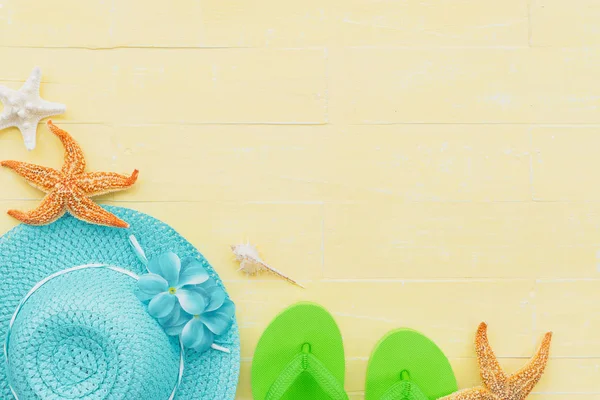 Güneş gözlüğü, deniz yıldızı, şapka plaj ve deniz kabuğu parlak sarı pastel ahşap arka plan üzerinde yaz tatil ve tatil kavramı için de dahil olmak üzere plaj aksesuarları.