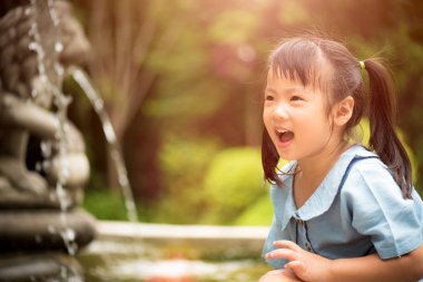 Sıcak yaz gününde renkli bahçe suda oynarken mutlu küçük kız. Çocuklar için yaz etkinlikleri.