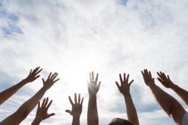 Many hands raised up against the blue sky. Friendship, Teamwork concept. clipart
