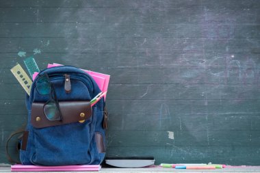 Okul sırt çantası ve okul malzemeleri kara tahta arka plan ile. Eğitim ve okul kavramı geri.