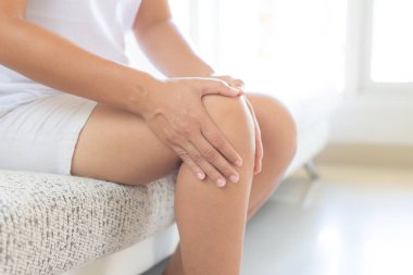 Kanepe ve duygu diz üzerinde oturan Closeup genç kadın acı ve o masaj evde onu diz. Sağlık ve tıp kavramı.