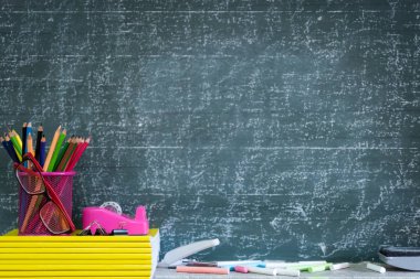 Eğitim ya da kavram okula geri. Gözlük, kalem, Not defterleri, tebeşir, kara tahta arka plan üzerinde silgi.