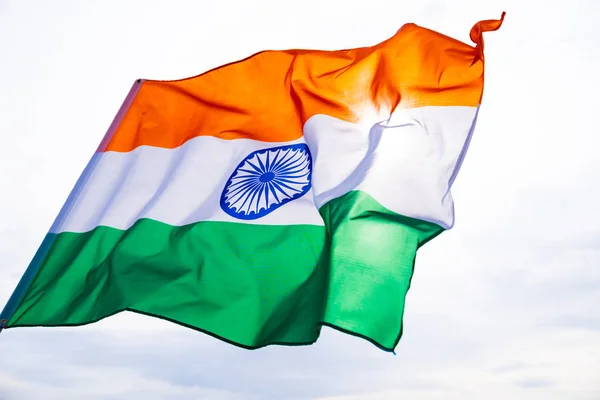 Close up man hand holding India flag on the blue sky background. Indian Independence Day, 15 August.