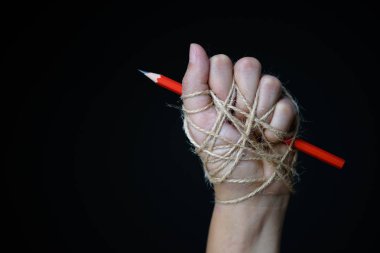 Kırmızı kalem eliyle basın özgürlüğü veya ifade özgürlüğü fikrine düşük anahtar içinde koyu arka plan üzerinde tasvir iple bağlı. Dünya basın özgürlüğü günü kavramı.