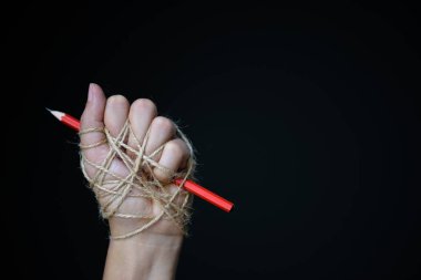 Kırmızı kalem eliyle basın özgürlüğü veya ifade özgürlüğü fikrine düşük anahtar içinde koyu arka plan üzerinde tasvir iple bağlı. Dünya basın özgürlüğü günü kavramı.