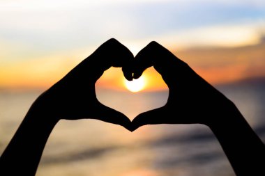 Siluet kadın kalp şekli günbatımı arka planda olmak eller. Mutlu, aşk, Sevgililer günü fikir, işaret, sembol, kavram.