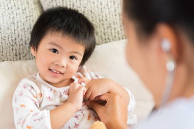 Doktor stetoskop kullanarak küçük bir kız İnceleme. Tıp ve sağlık kavramı.