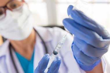 Omzunda steteskop olan kadın doktor şırınga ve aşı tutuyor. Sağlık ve Tıp Konsepti.