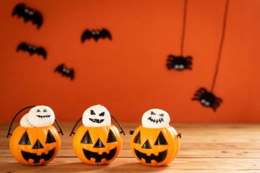 Cadılar Bayramı el sanatları, Turuncu kabak, hayalet ve ahşap masa ve turuncu arka plan kopya alanı için metin ile maça. Cadılar Bayramı kavramı.