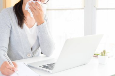 Genç iş kadını ofiste, s doku ve neezing beyaz mendil tutan el hasta. Masa üstünde Laptop. Sağlık ve tıp kavramı.