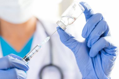Omzunda steteskop olan kadın doktor şırınga ve aşı tutuyor. Sağlık ve Tıp Konsepti.
