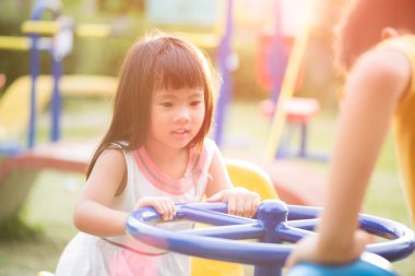 Sıcak bir yaz günü güneşli Şehir parkındaki bir salıncak yolculuk zevk Bahçesi eğleniyor mutlu küçük kız.