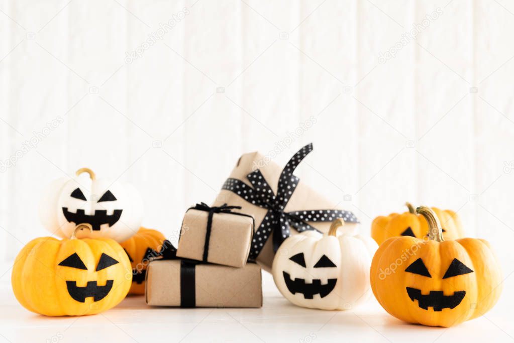 Yellow and white ghost pumpkin with gift box on white brick block background. halloween concept.
