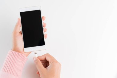 Bağlantı şarj cihazı beyaz masa artalanını smartphone için eller kadın.