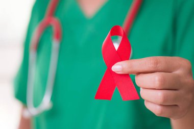Kadın doktor stetoskop bir kırmızı kurdele HIV, Dünya AIDS Günü bilinçlendirme şerit tutan omuz ile. Sağlık ve tıp kavramı.