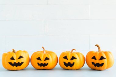 Sarı hayalet beyaz tuğla blok arka plan üzerinde kabak yığını. Cadılar Bayramı kavramı.