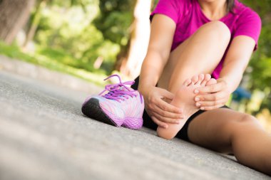 Genç kadın egzersiz ve spor ve egzersiz kavramı çalıştıran acı onun ayak Masaj.