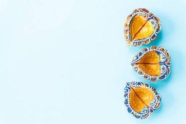 Mutlu bayramlar - Clay Diya lambalar Dipavali, ışıklar kutlama Hindu festivali sırasında yaktı. Camgöbeği arka plan üzerinde renkli geleneksel yağ lambası diya