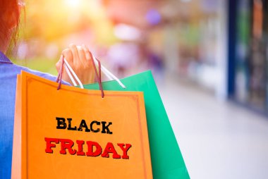 Black Friday kelime konsepti ile alışveriş merkezi alışveriş torbaları tutan kadın.