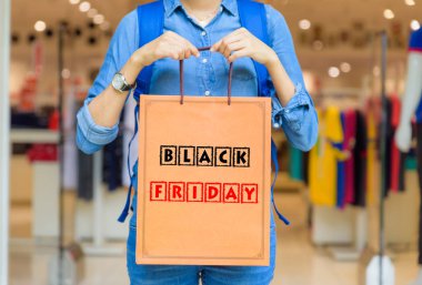 Black Friday kelime konsepti ile alışveriş merkezi alışveriş torbaları tutan Closeup kadın.