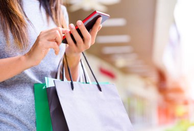 Alışveriş torbaları üzerinde cep telefonu süpermarket online alışveriş yaparken tutan kadın. Siyah Cuma satış konsepti.