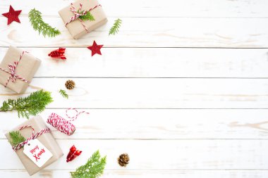 Noel ve yeni yıl kompozisyon. Ahşap beyaz zemin üzerine hediye kutusu, çam kozalakları, kızıl yıldız ve çan üstten görünüm.