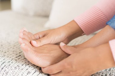 Koltukta oturan Closeup kadın onun ayak yaralanma ağrı hissi tutar. Sağlık ve tıp kavramı.