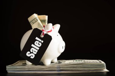 Alışveriş satış kavramı kırmızı bilet satış etiketiyle kumbara ile Amerika doları banknot para yığını üzerinde asılı.